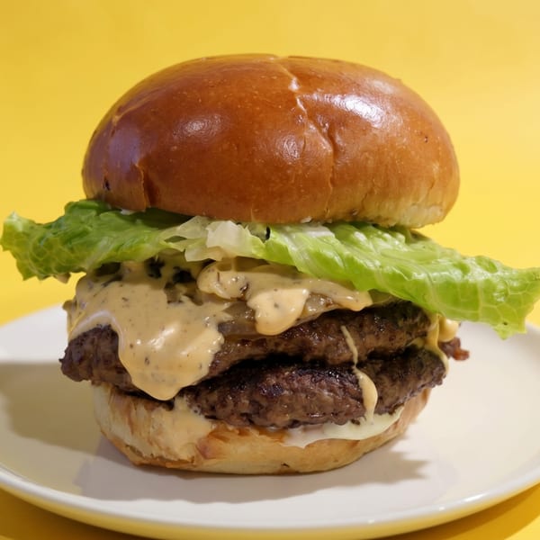 A double patty burger with melted cheese, lettuce, and special sauce on a brioche bun.